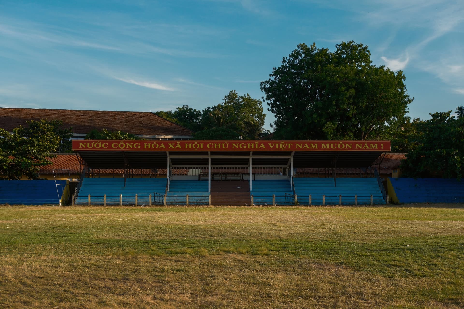 Empty small-town football stand with a red banner, lit by late afternoon sun